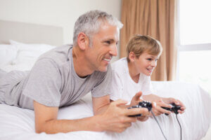 Far og søn spiller videospil i sengen